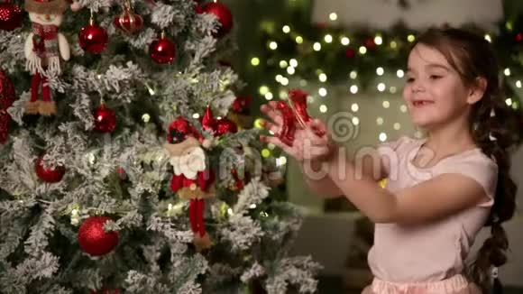 一个六岁的小女孩扎着辫子装饰了一棵圣诞树以马的形式悬挂玩具视频的预览图
