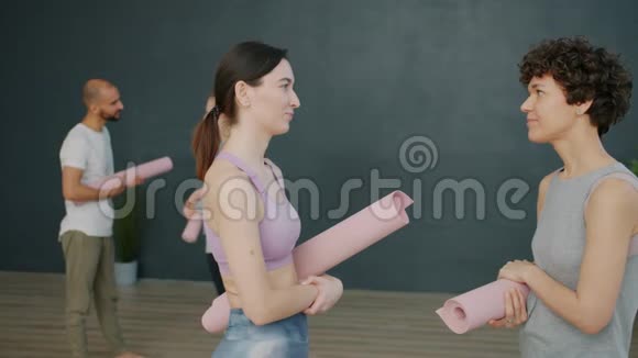 迷人的运动女孩在现代运动中心拿着瑜伽垫谈笑风生视频的预览图