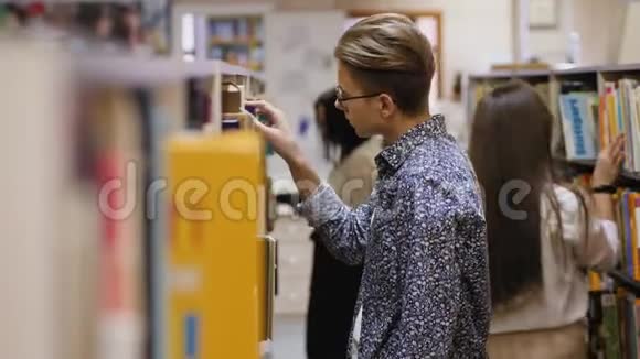 一个戴眼镜的年轻人在图书馆一本书视频的预览图