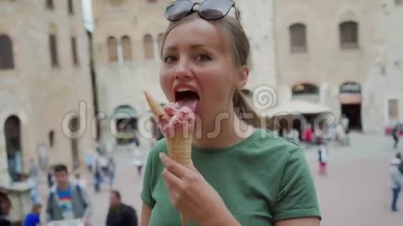 年轻女人吃粉红色冰淇淋筒和意大利冰淇淋背景模糊视频的预览图