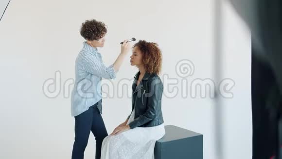 在后台与化妆师合作的美国黑人女士模特视频的预览图