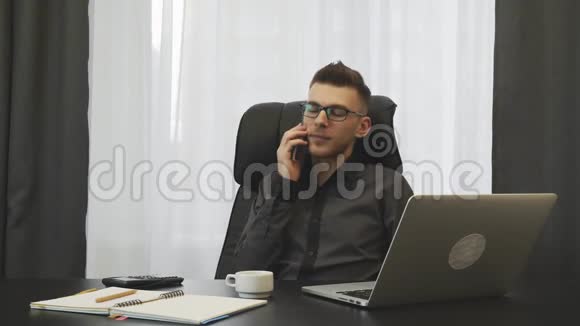 成功的年轻商人在他的现代办公室打电话男人在智能手机上与合作伙伴交谈并达成交易雄性鳍视频的预览图