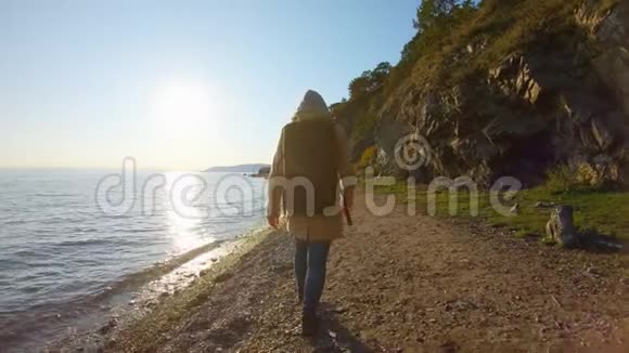 日落时分背着背包的女孩在海边散步视频的预览图