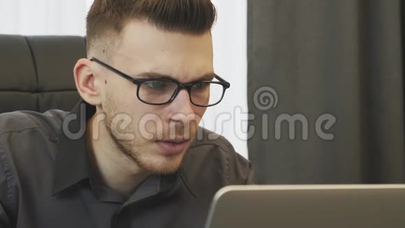 网上看到的新闻震惊了人们戴眼镜的商人在笔记本电脑屏幕上阅读公司的不良评论男性视频的预览图