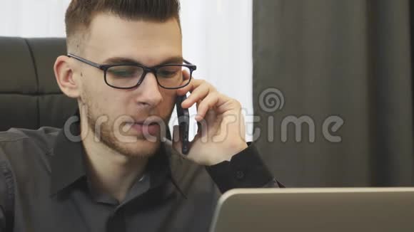 在办公室打电话的人关闭视野戴眼镜的成功商人在电话里交谈看着笔记本电脑屏幕港口视频的预览图