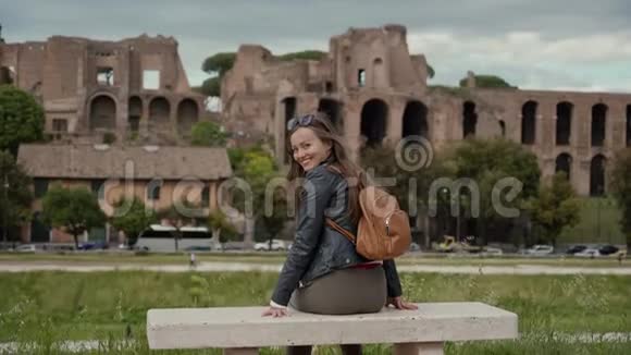 意大利罗马阳光明媚的一天快乐的女游客坐在石凳上俯瞰马戏团的古老遗址视频的预览图