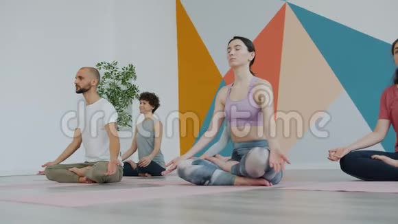 瑜伽的学生在莲花的位置放松双手在Namaste冥想视频的预览图