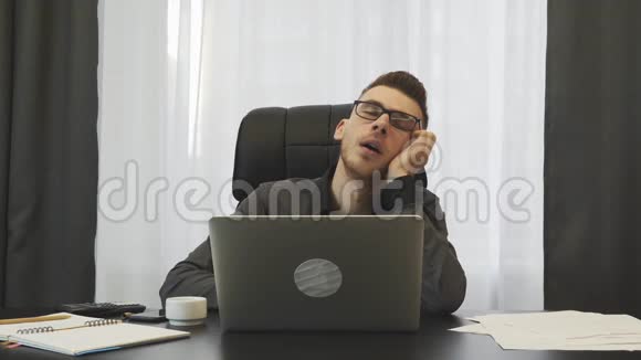 在工作场所睡觉的人疲惫的家伙坐在办公桌前差点摔倒经纪人在办公室里揉眼睛青年视频的预览图