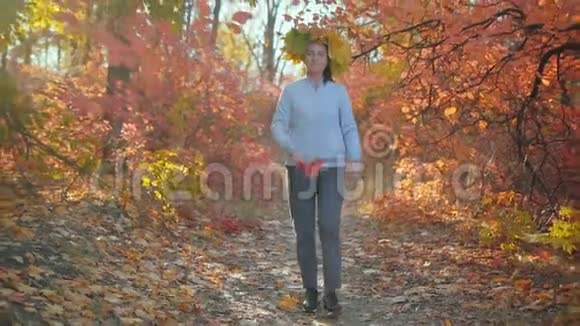 慢动作美丽的女人秋叶的呼吸沿着森林的小径和溪流视频的预览图