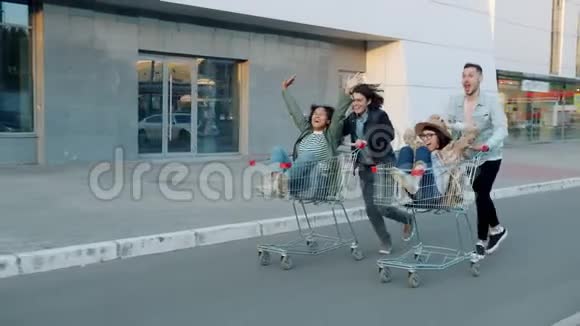 快乐的年轻人朋友在户外骑着购物车慢动作视频的预览图