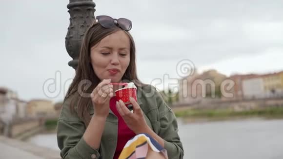 一位美丽的年轻女子坐在长廊上享用意大利冰淇淋和草莓视频的预览图