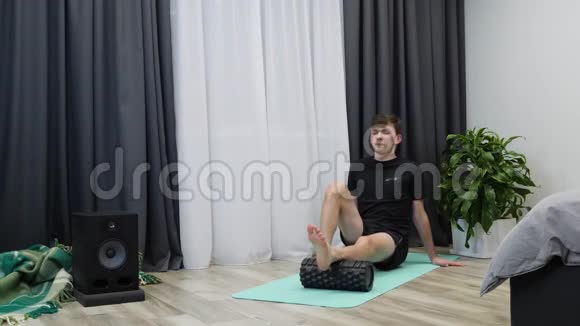 男性练习肌筋膜释放使用健身滚筒在家里健身教练在训练后进行腿部肌肉按摩视频的预览图