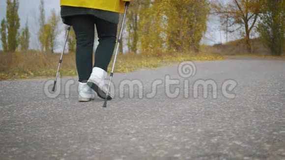 在秋天的森林里做北欧行走的高级妇女在秋天的小径上进行北欧步行比赛退休人士健康视频的预览图