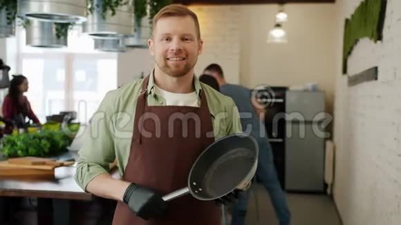 烹饪课上长得好看的年轻人拿着煎锅的慢镜头画像视频的预览图
