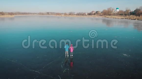 在一个可爱的阳光明媚的冬日在冰冻的湖面上观看快乐的夫妇在户外滑冰滑冰可爱的情侣视频的预览图