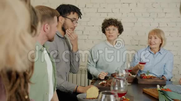 人们在室内与食物和饮料一起坐在桌旁说话的慢动作视频的预览图