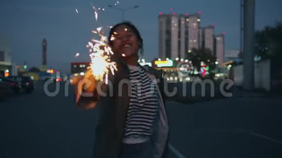 可爱的非裔美国女孩晚上在城市里跳舞手里拿着孟加拉灯视频的预览图