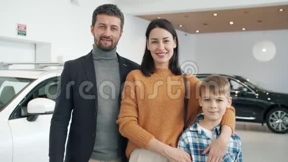 幸福家庭的慢动作与儿子微笑在汽车经销商站在一起视频的预览图