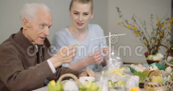老人和孙女装饰桌与复活节彩蛋和复活节装饰视频的预览图