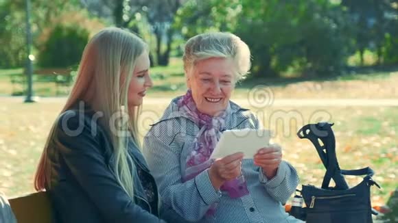 中近的老妇人在公园里读一封给漂亮年轻女人的信视频的预览图