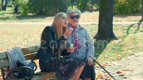 快乐的年轻女子和她的祖母坐在一起吹泡泡视频的预览图