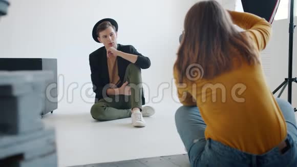 在摄影棚为女摄影师摆姿势的时髦男人视频的预览图