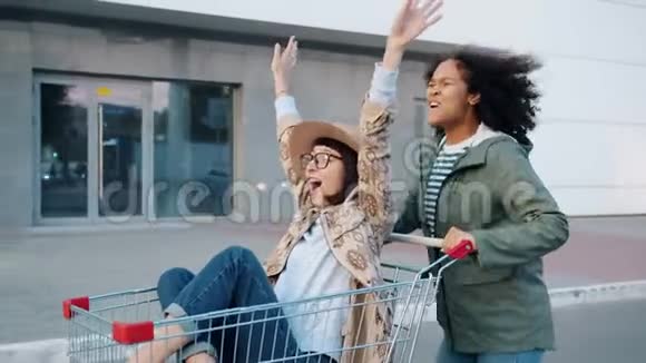 混合种族的女孩推着购物车和女朋友玩视频的预览图
