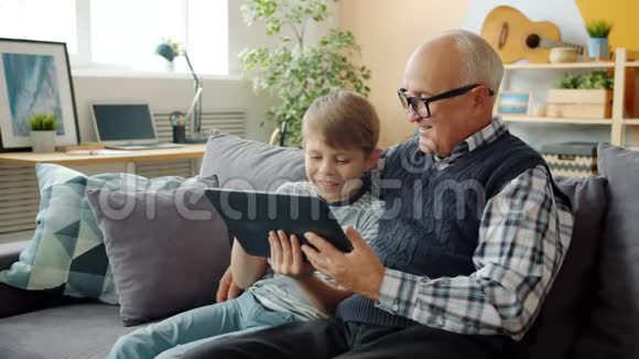 老人和快乐男孩用平板电脑聊天享受闲暇时光和小玩意视频的预览图