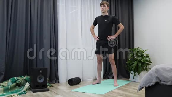 年轻的白种人男孩在室内做健身运动适合穿黑色运动服的运动男子做有氧运动和瑜伽康复训练视频的预览图