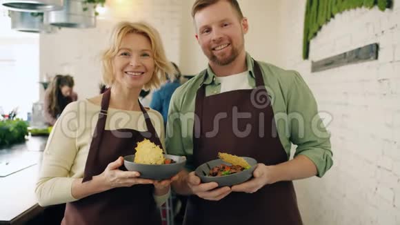 在烹饪学校里男人和女人站在一起拿着盘子的画像视频的预览图