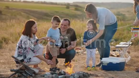 一家人和孩子们在篝火旁野餐视频的预览图