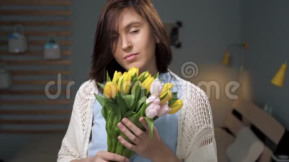 有花的女孩迷人的年轻女子手里拿着一束黄色郁金香看着相机带来了植物视频的预览图