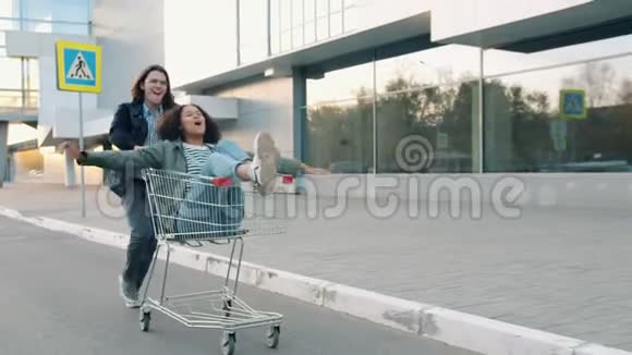 帅哥推着购物车和混血女孩在外面玩得很开心视频的预览图