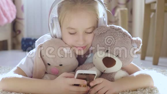 一个女孩在房间里的地板上玩手机还有她最喜欢的玩具视频的预览图