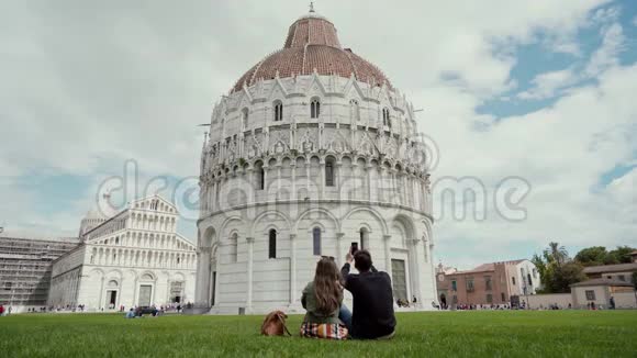 年轻人坐着用电话拍下著名建筑比萨后视图视频的预览图