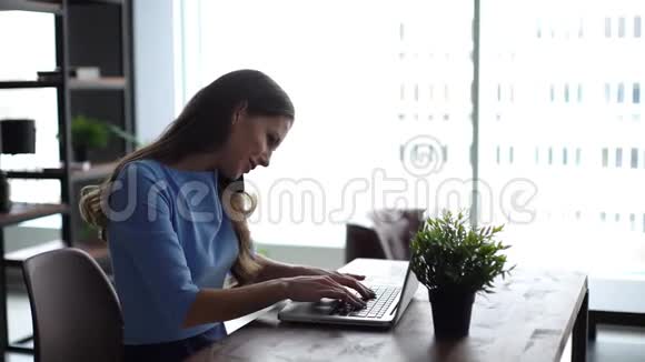 年轻的上班族妇女坐在办公桌前用笔记本电脑在电话里交谈视频的预览图