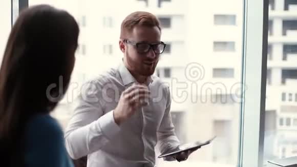 自信的年轻商人戴着眼镜手里拿着一块平板电脑解释道视频的预览图