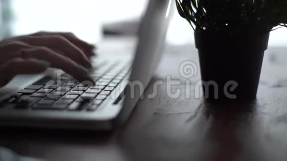 女人的手在桌旁笔记本电脑键盘上缓慢地打字视频的预览图