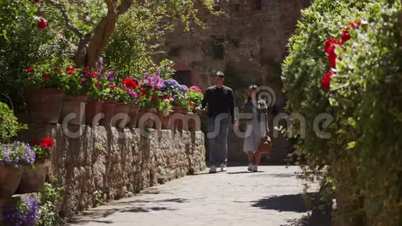 年轻人牵着手沿着彩色花坛漫步在老城区视频的预览图