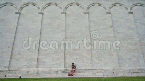 美丽的女孩坐在意大利地标大理石墙附近的电话一般短视频的预览图
