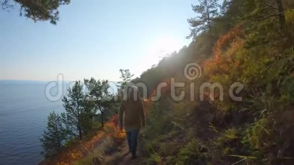 女孩爬上陡峭的海岸明亮的秋日照耀着视频的预览图