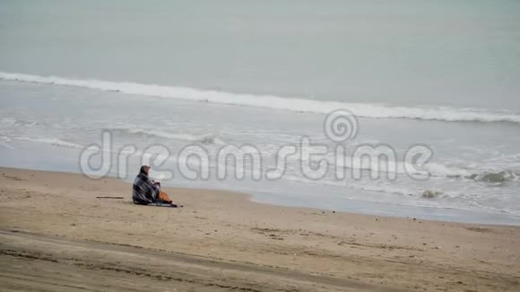 风天坐在海边舒适温暖的毯子里的女人看书一般短视频的预览图