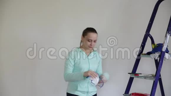 一名年轻妇女戴上呼吸器和手套开始在油漆前对墙壁进行打磨视频的预览图