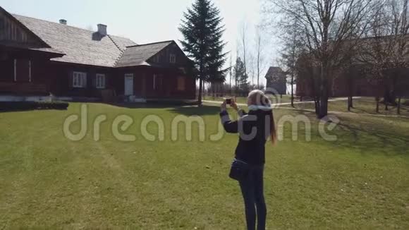 女游客在一个古老的欧洲村庄里拍了一张木屋的照片视频的预览图