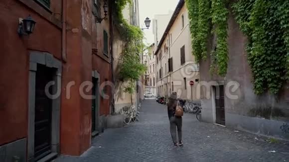 年轻的女游客沿着罗马狭窄舒适的街道散步后视图视频的预览图
