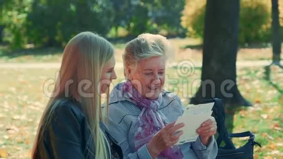 中近的老妇人在公园里读一封给漂亮年轻女人的信视频的预览图