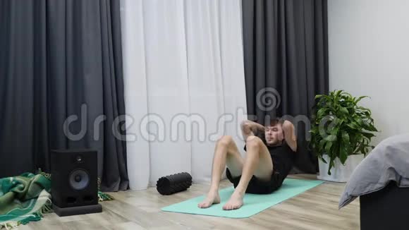 男人在家里做腹肌练习在地板上打盹安装人泵压力和做锻炼训练健身男孩抽肌肉视频的预览图