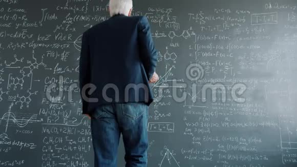 聪明的老人走在黑板上在大学教室里拿着公式视频的预览图