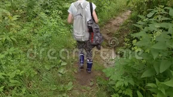 春天一个徒步旅行者沿着森林小路走过小溪一个背着背包的少年视频的预览图