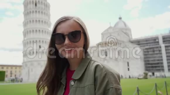 戴着太阳镜的漂亮微笑的女人站在比萨大教堂和斜塔附近视频的预览图